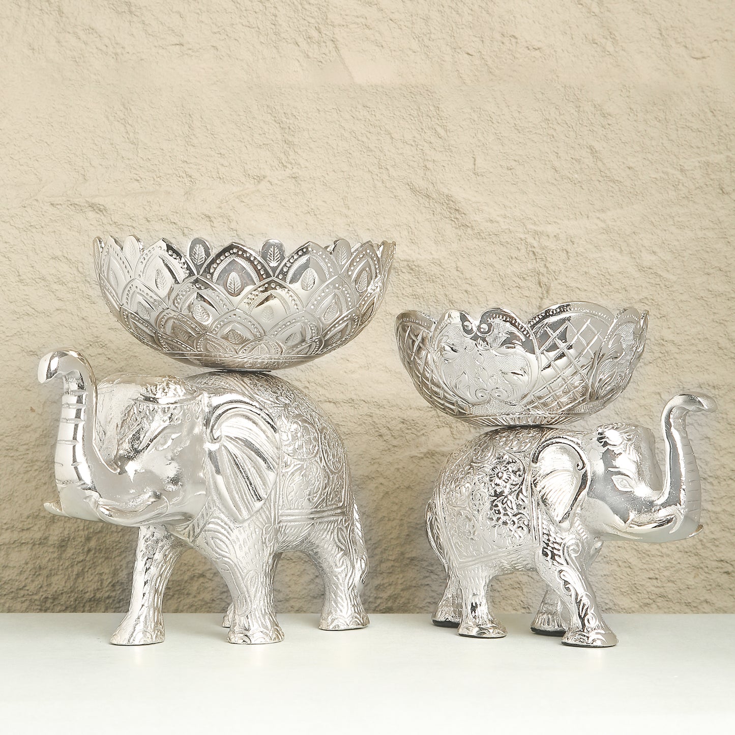 Two silver elephant-shaped bowls with intricate designs on a neutral background