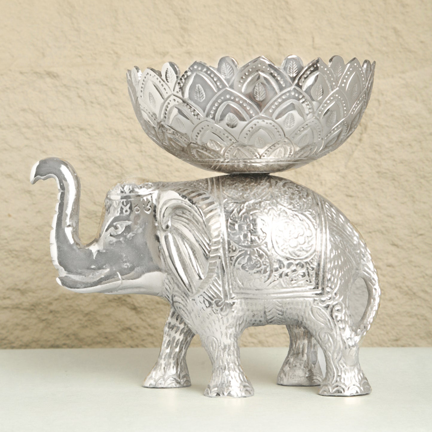 Decorative silver elephant with a matching bowl on a beige background
