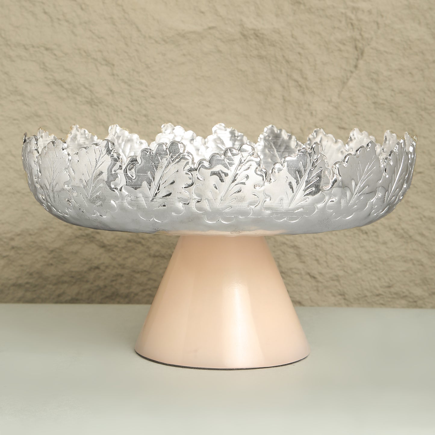 Decorative bowl with intricate design on a stand against a neutral background