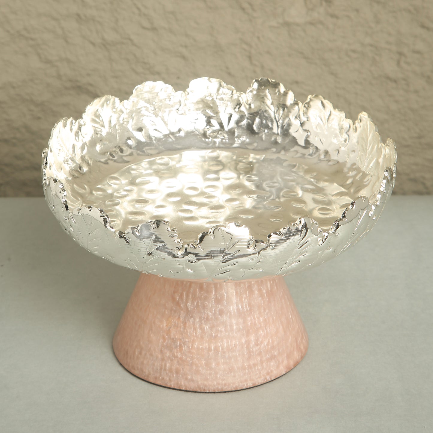 Decorative bowl with textured surface on a stand against a neutral background