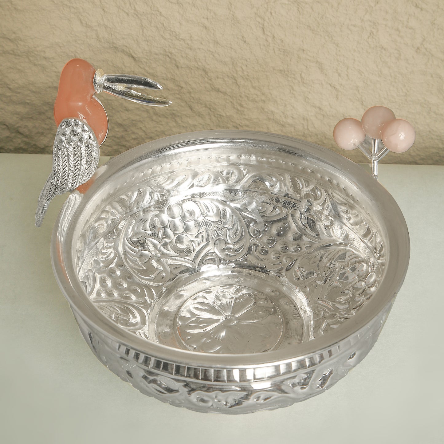 Decorative silver bowl with intricate designs on a neutral background
