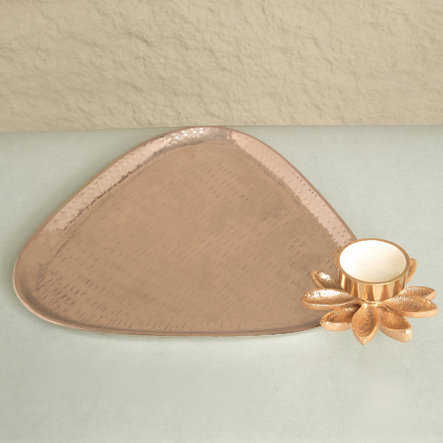 Decorative copper tray with a floral design on a light green surface