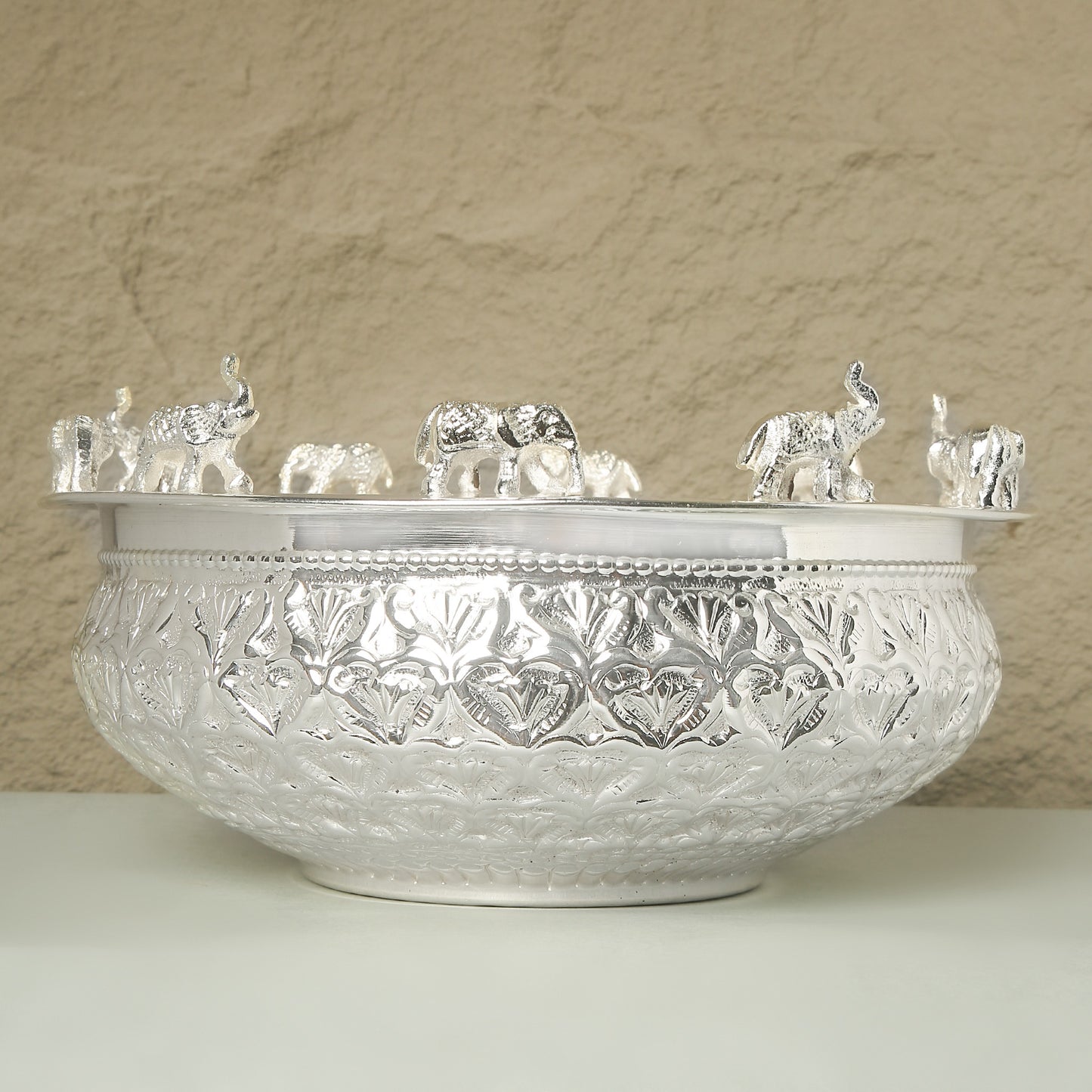 Decorative crystal bowl with intricate patterns and small crystal elephants on a beige background