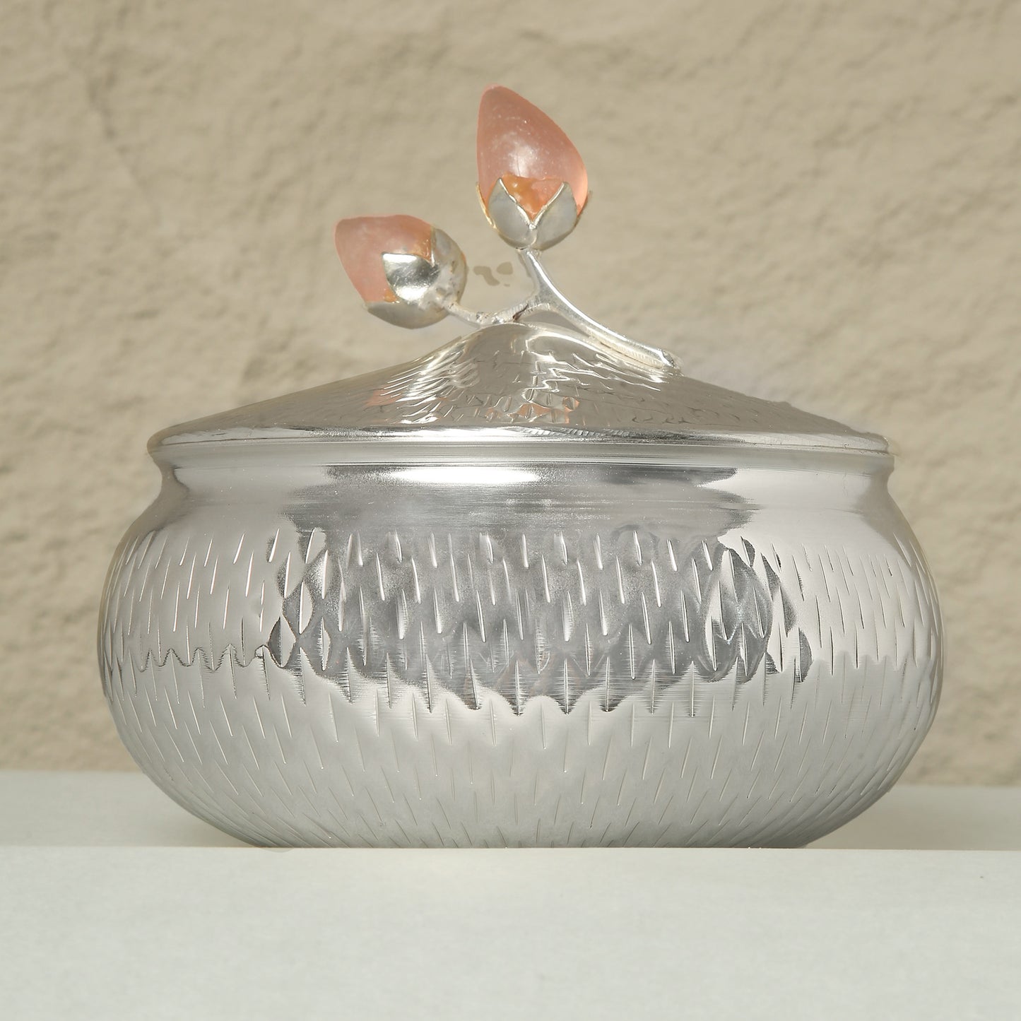 Silver textured container with a lid featuring a flame design on a beige background