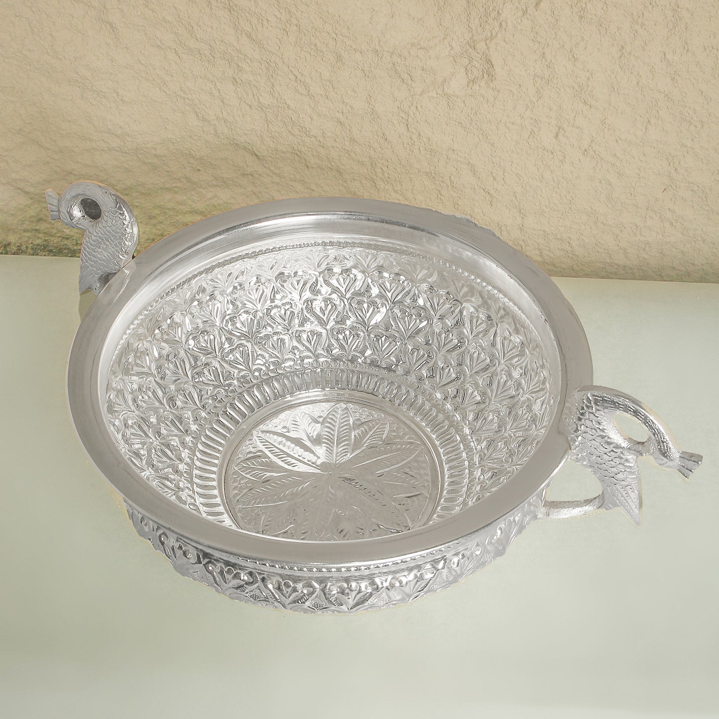 Decorative silver bowl with intricate patterns on a light background