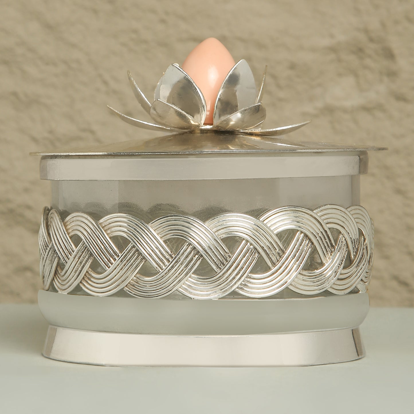Decorative container with silver lid featuring a floral design on a neutral background