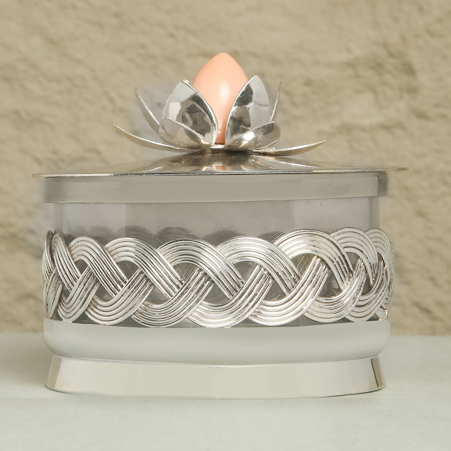 Decorative container with silver lid featuring a floral design on a beige background