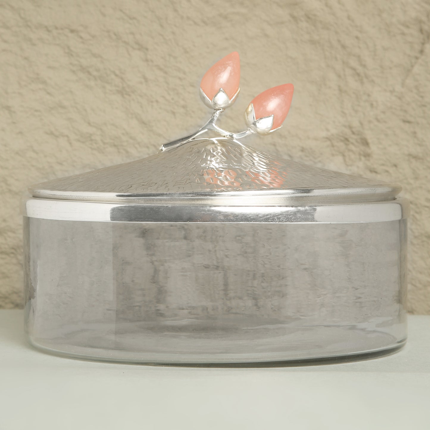 Silver container with a decorative lid featuring pink flowers on a beige background