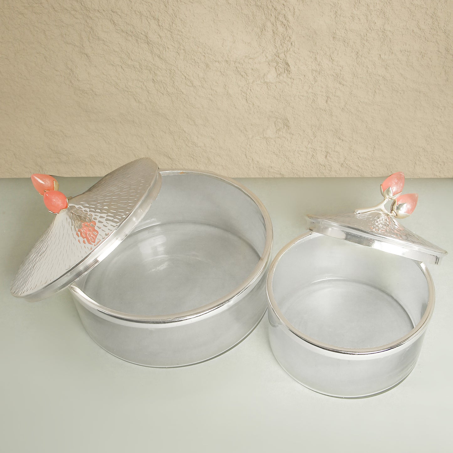 Two metallic cake tins with decorative lids on a light surface.