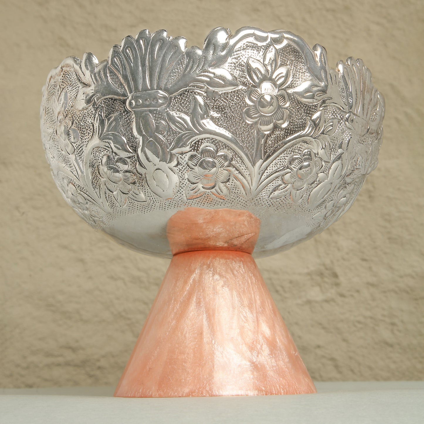 Decorative silver bowl with floral patterns on a beige background