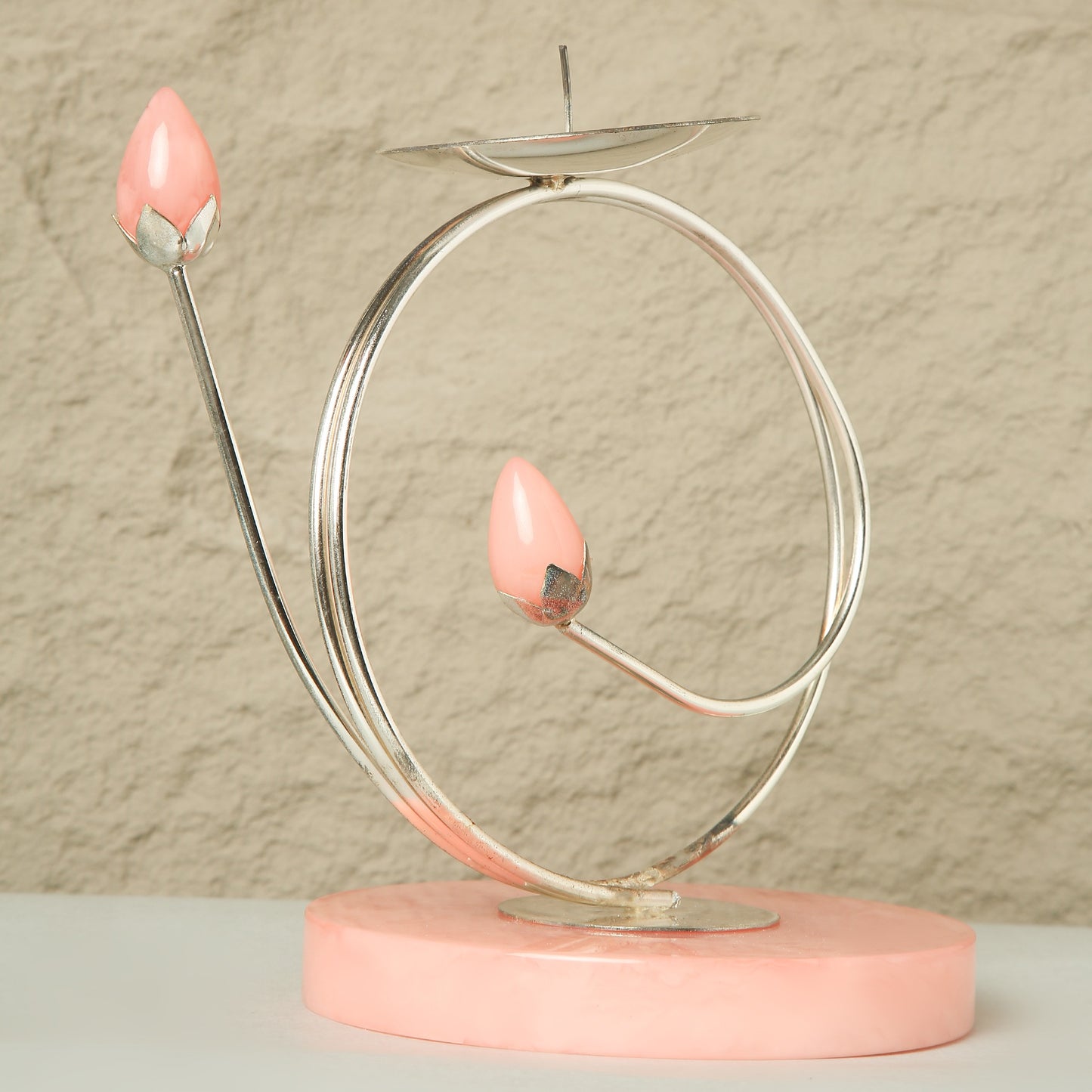 Decorative object with pink base and pink teardrop-shaped candles on a beige background