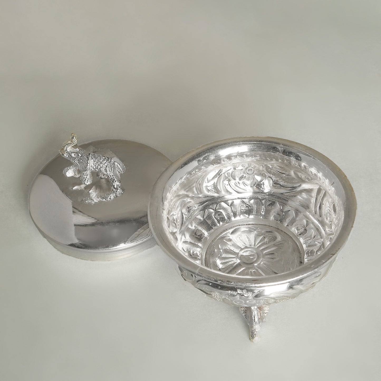 Silver decorative bowl with intricate designs on a light gray background