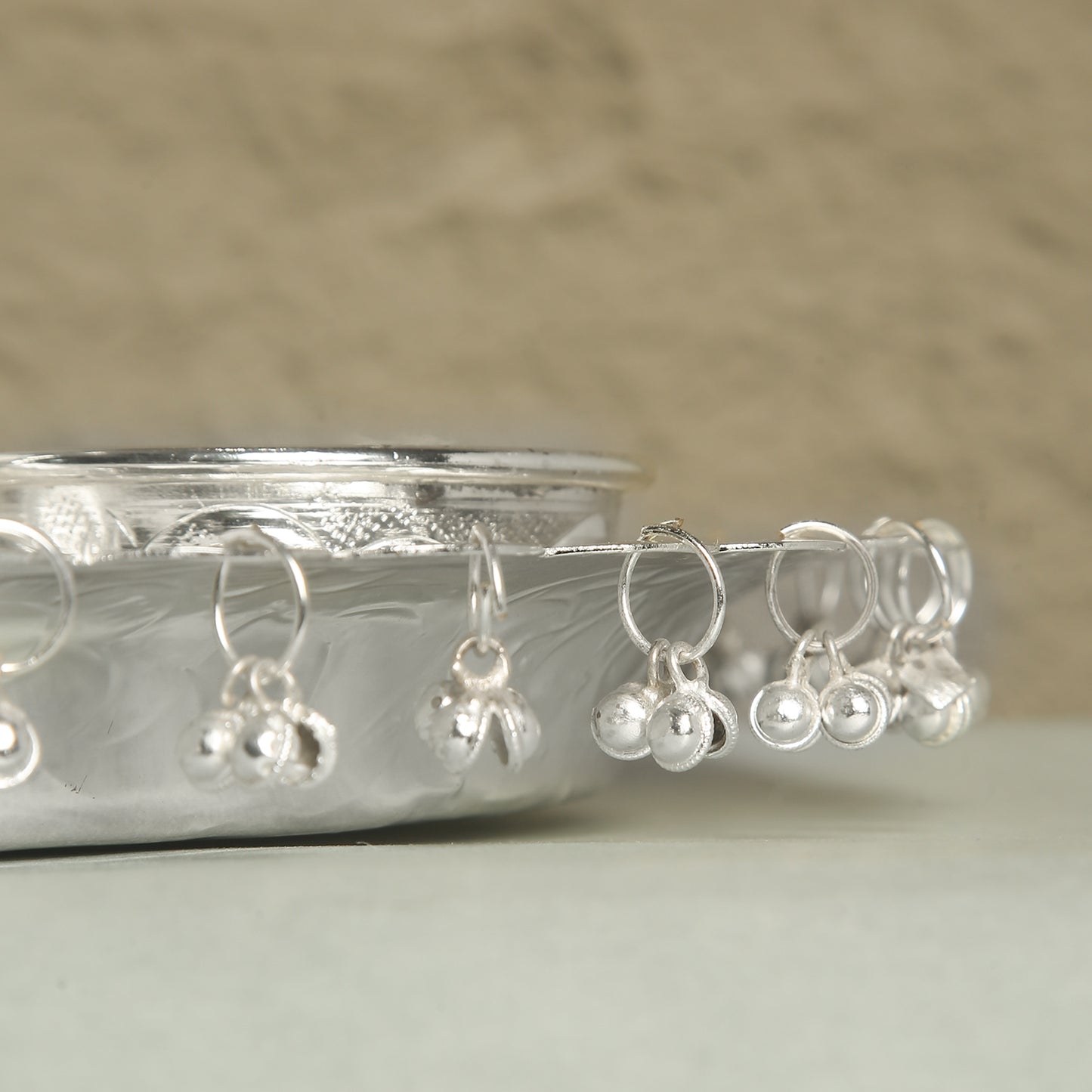 Silver wine glass charms with pearl-like beads on a white surface.