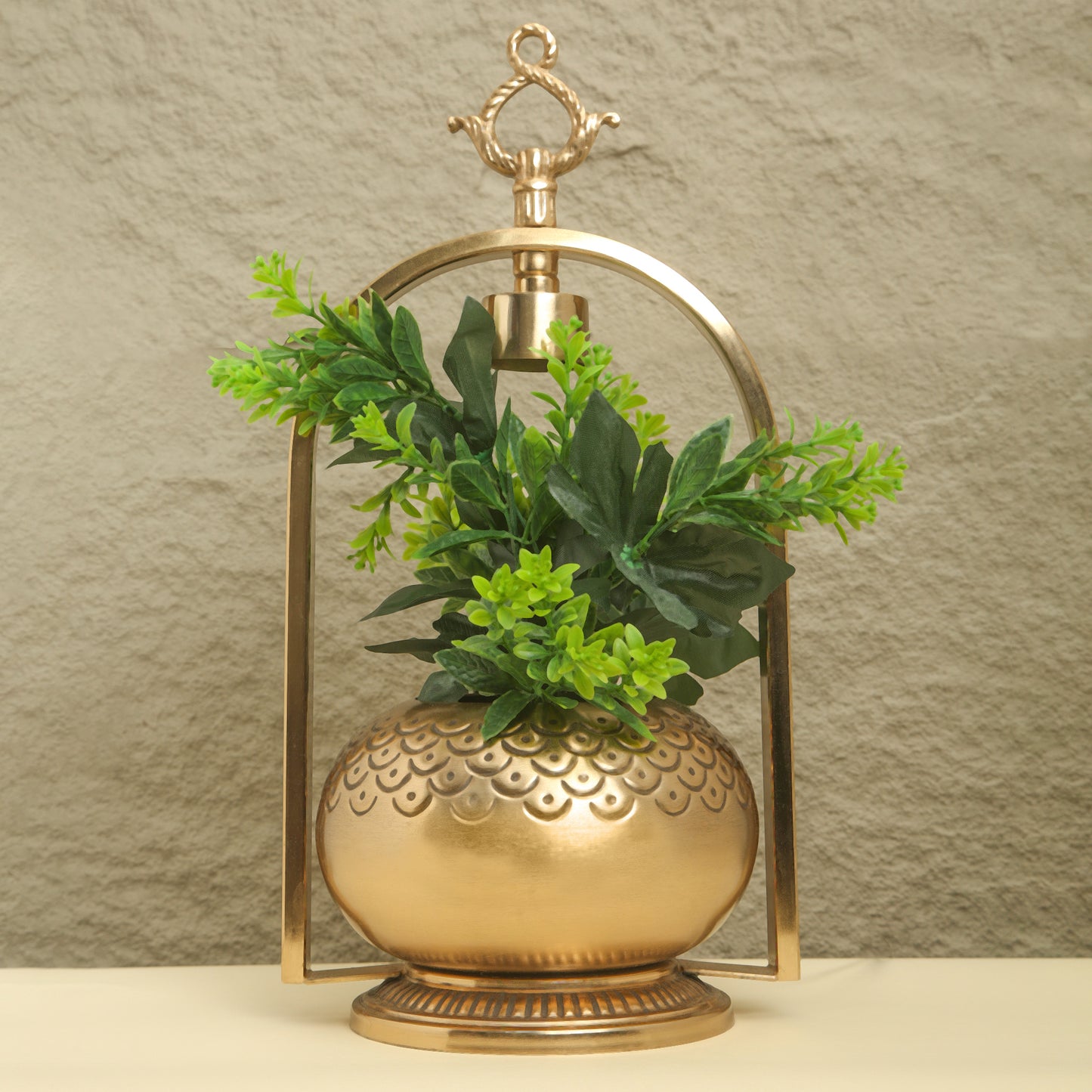 Decorative gold lantern with green plants against a beige background