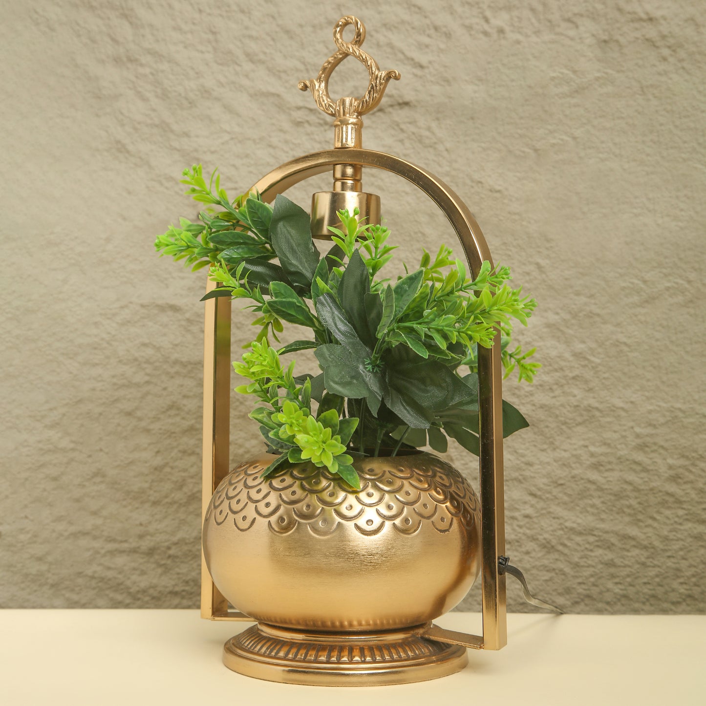 Decorative gold lantern with green plants against a neutral background
