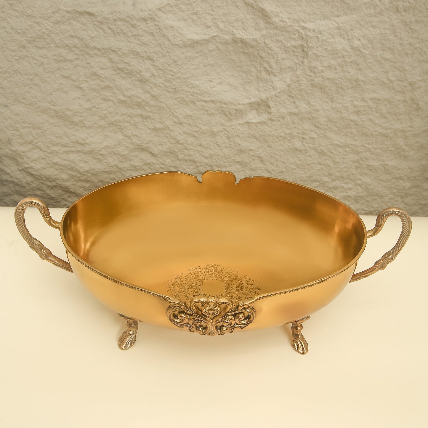 Gold ornate bowl with handles on a light background