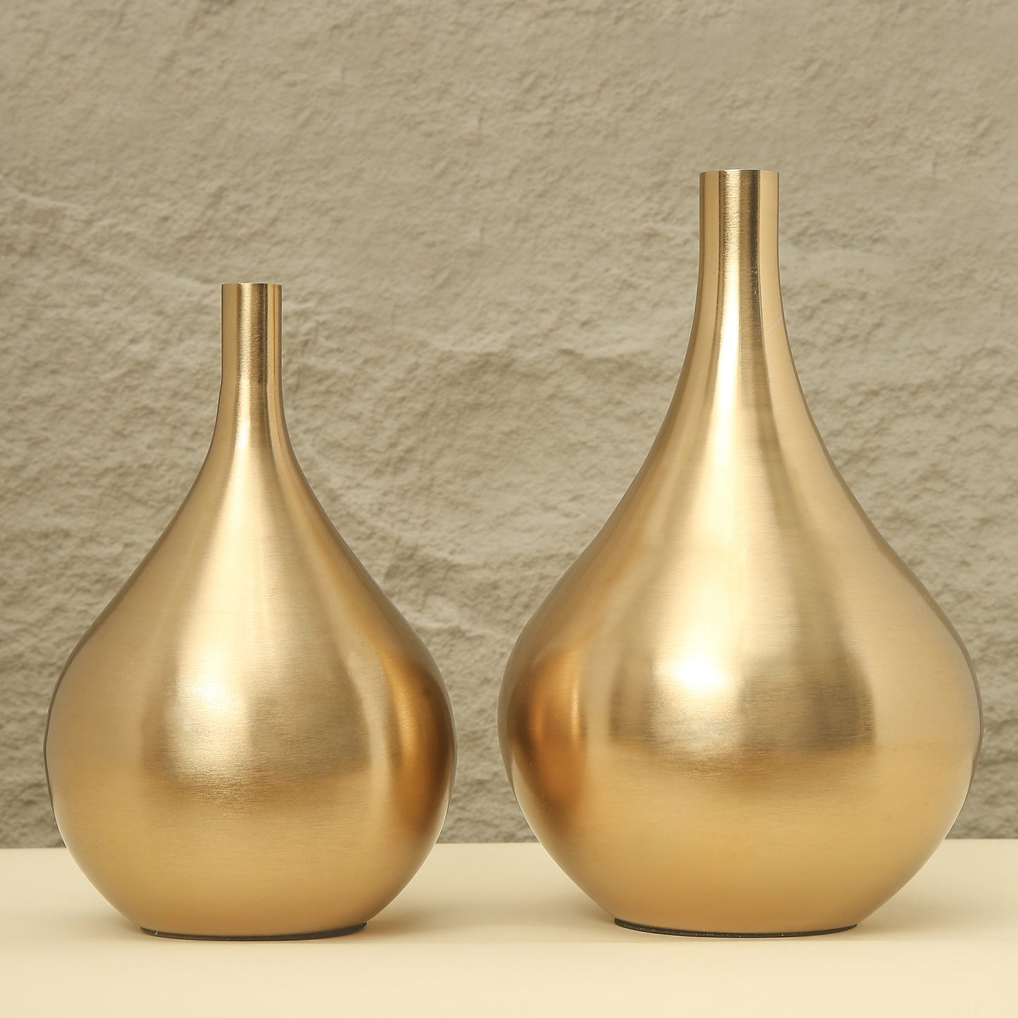 Two gold vases on a neutral background