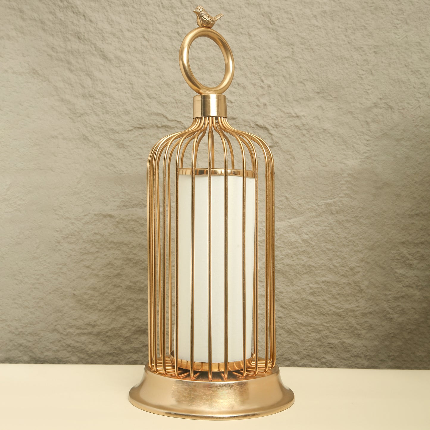Gold birdcage-style lantern with a white candle on a neutral background