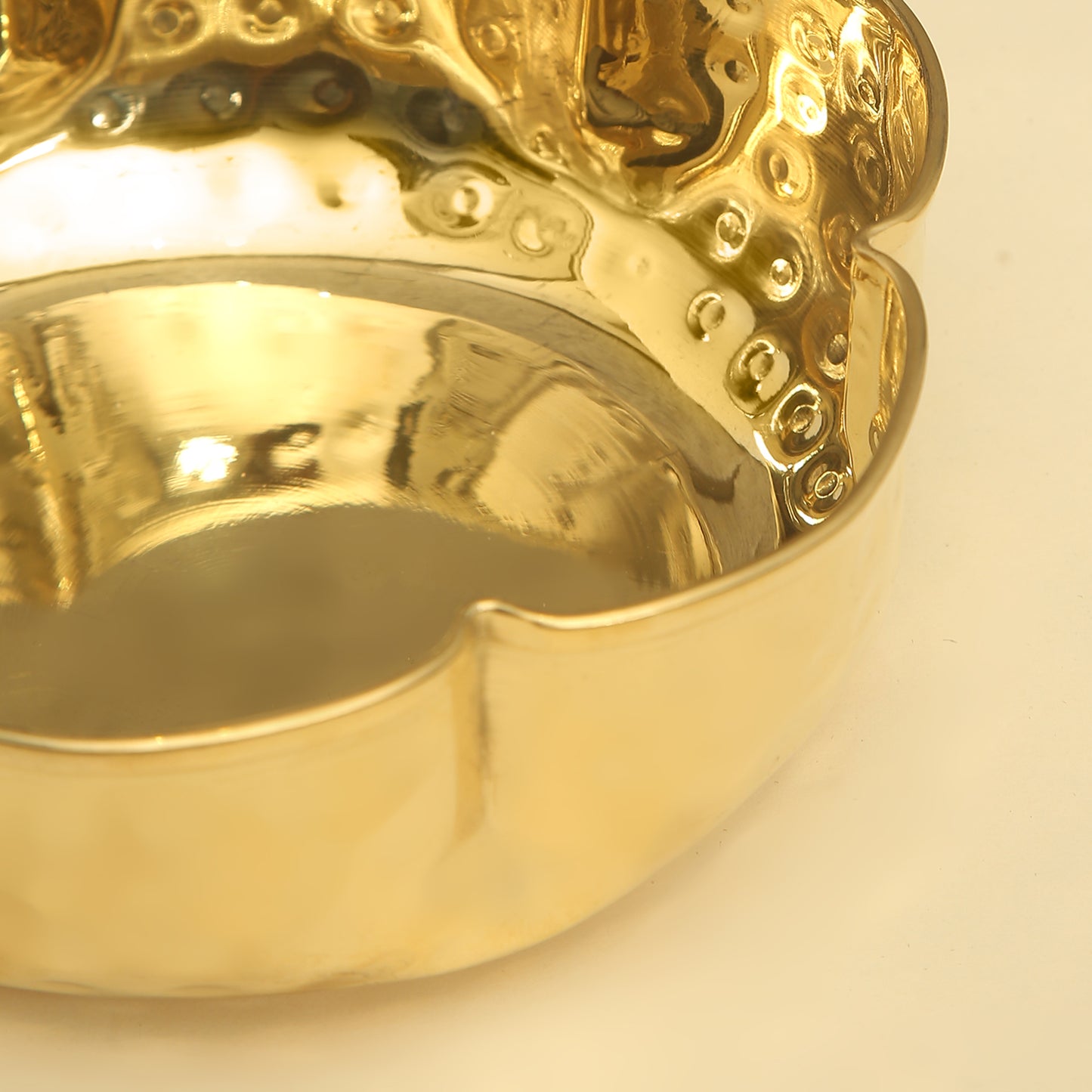 Gold ring with intricate design on a light beige background