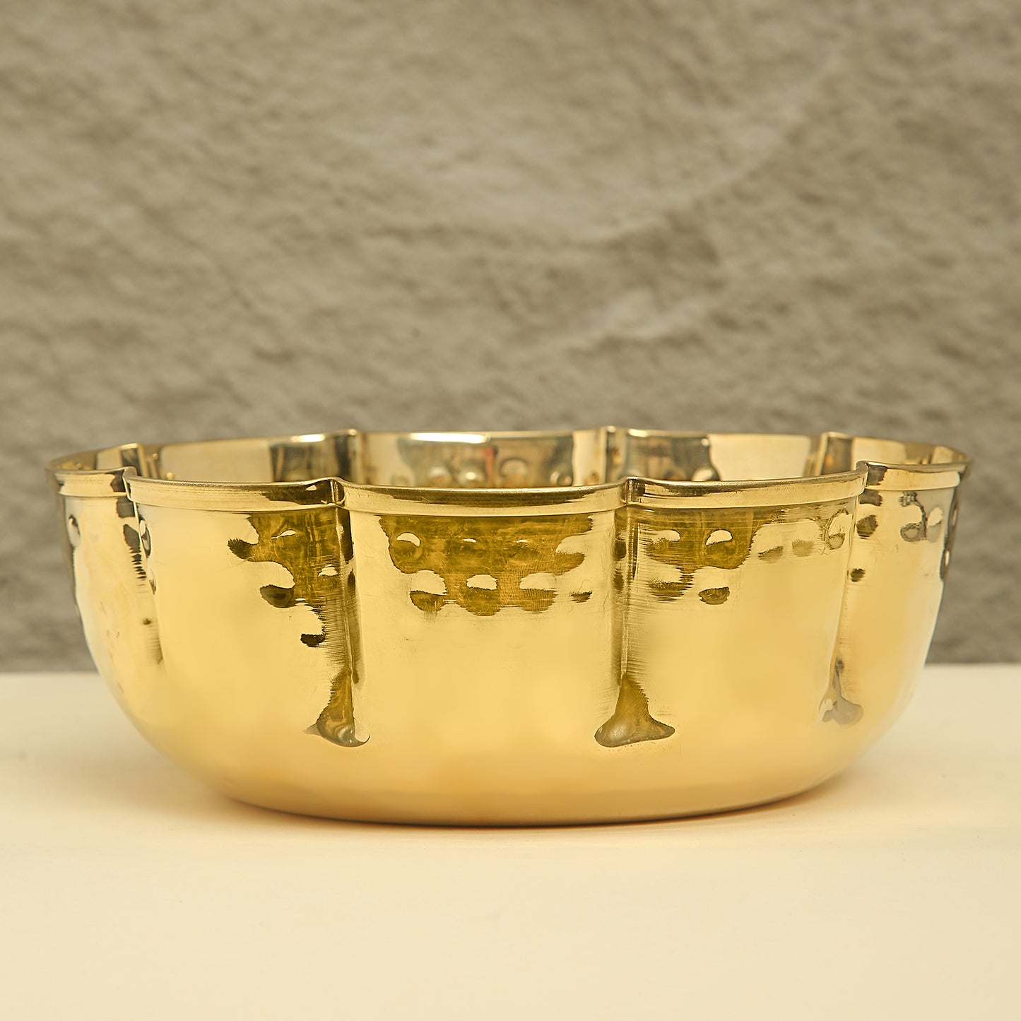 Gold decorative bowl with intricate designs on a neutral background