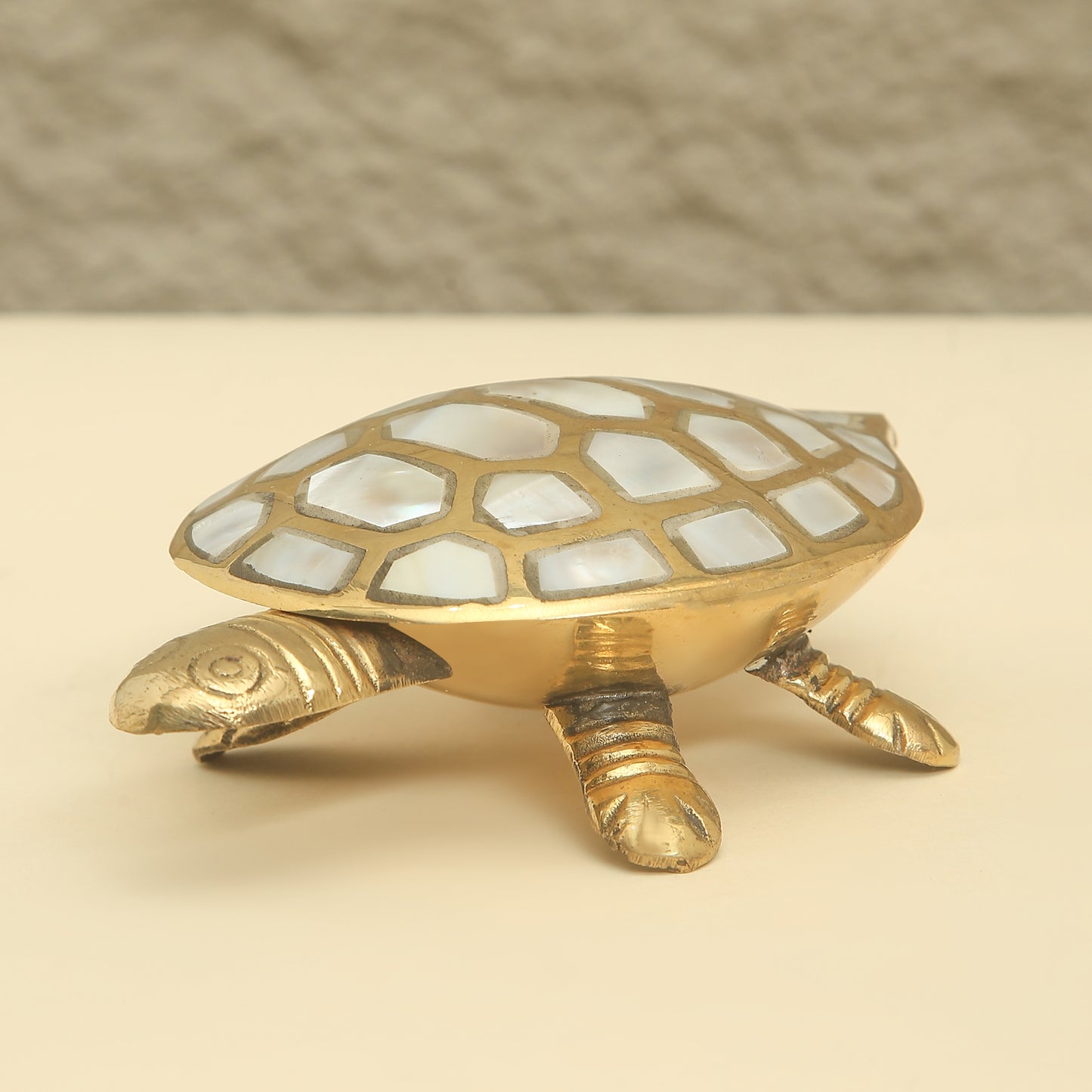 Decorative turtle figurine with a shell made of small stones on a beige background