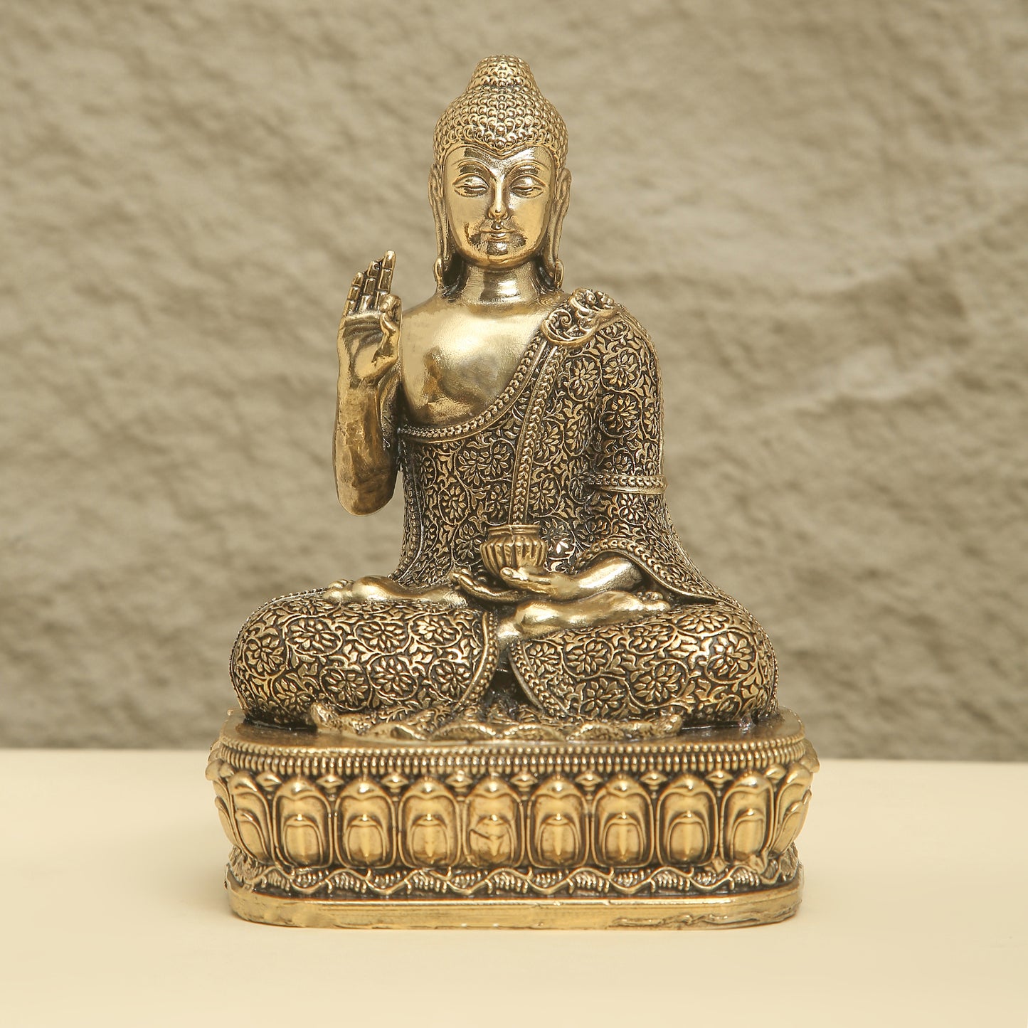 Bronze statue of a seated Buddha on a textured surface