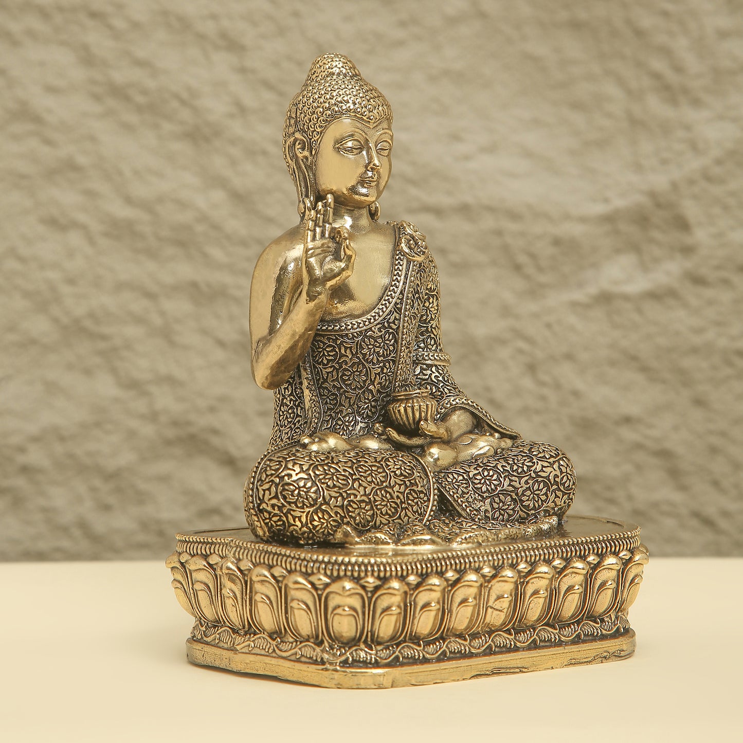 Bronze statue of a seated Buddha on a textured surface