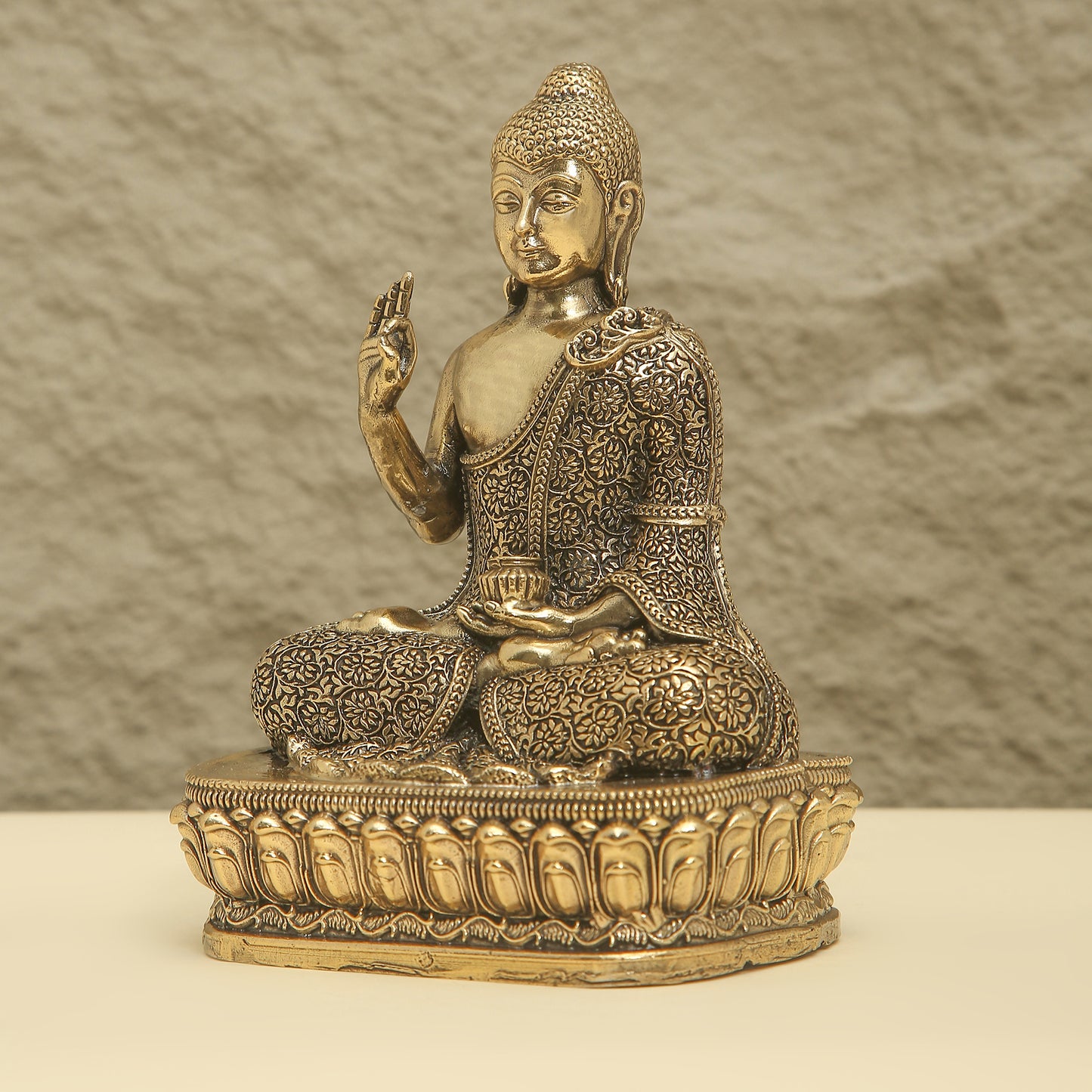 Bronze statue of a seated Buddha with intricate details on a textured background