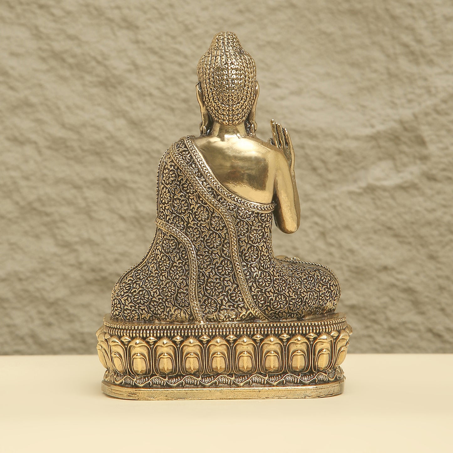 Bronze Buddha statue with intricate designs on a textured background