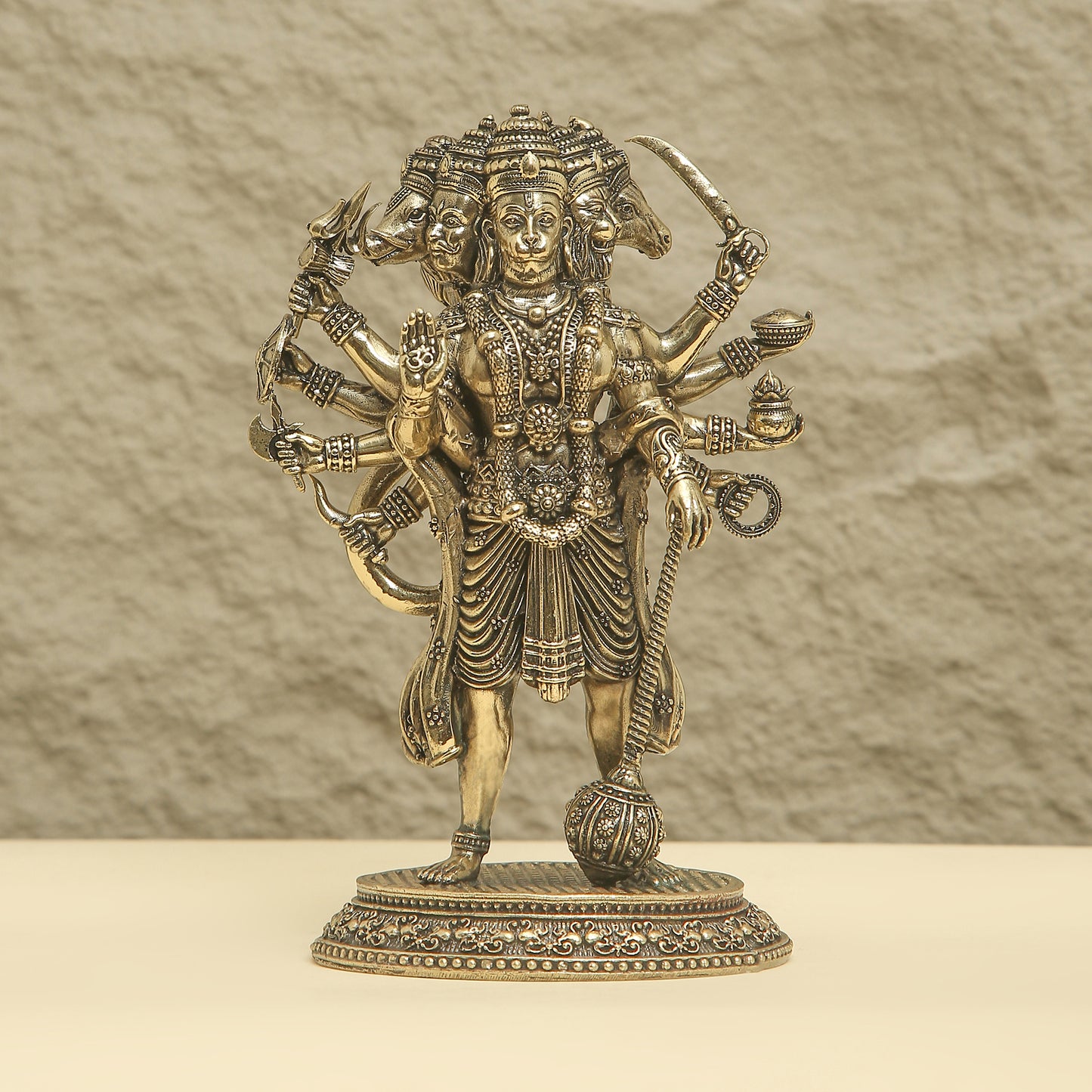 Bronze statue of a deity with multiple arms on a beige background