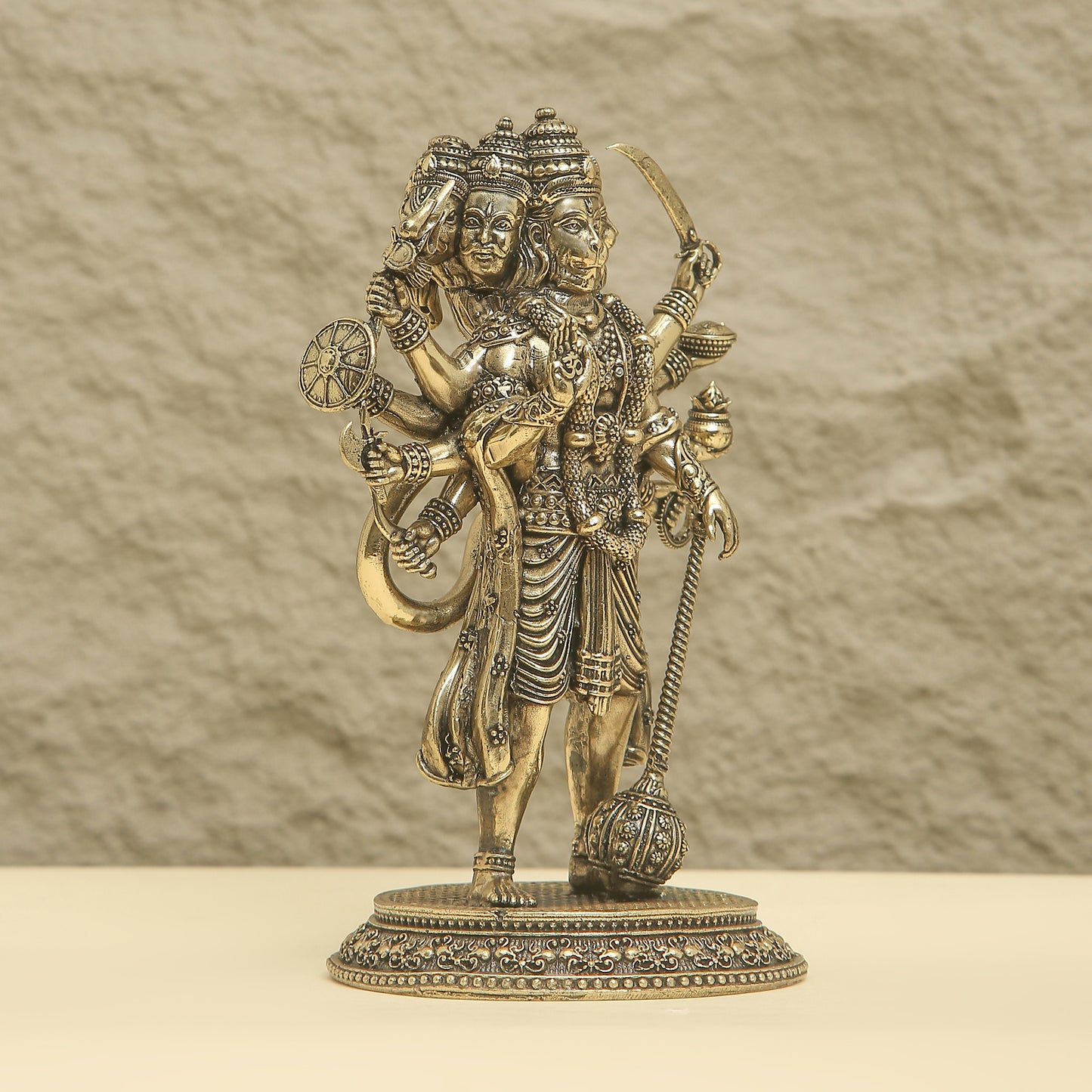 Bronze statue of a deity with intricate details on a beige background