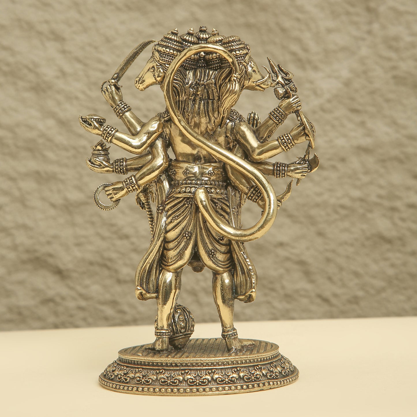 Bronze statue of a deity with multiple arms and a snake on a beige background