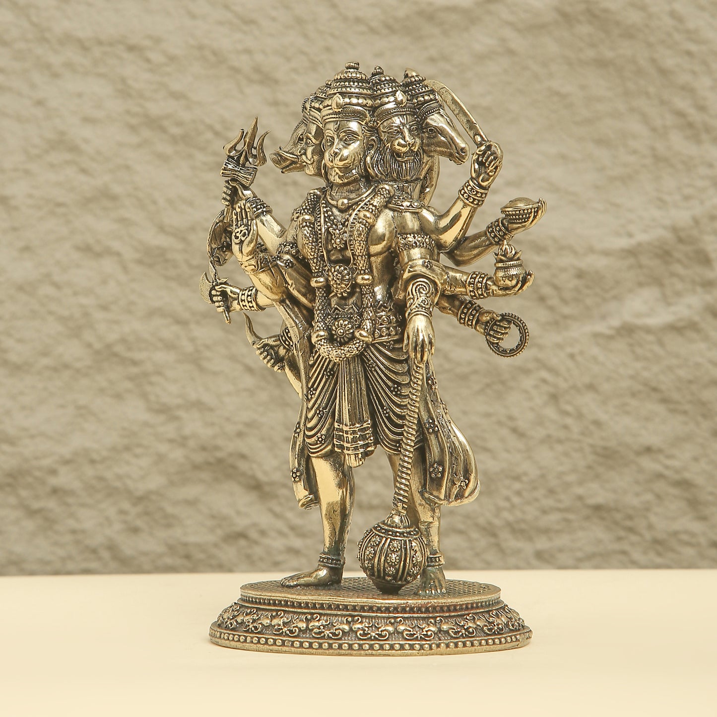Bronze statue of a deity with multiple arms and weapons on a beige background