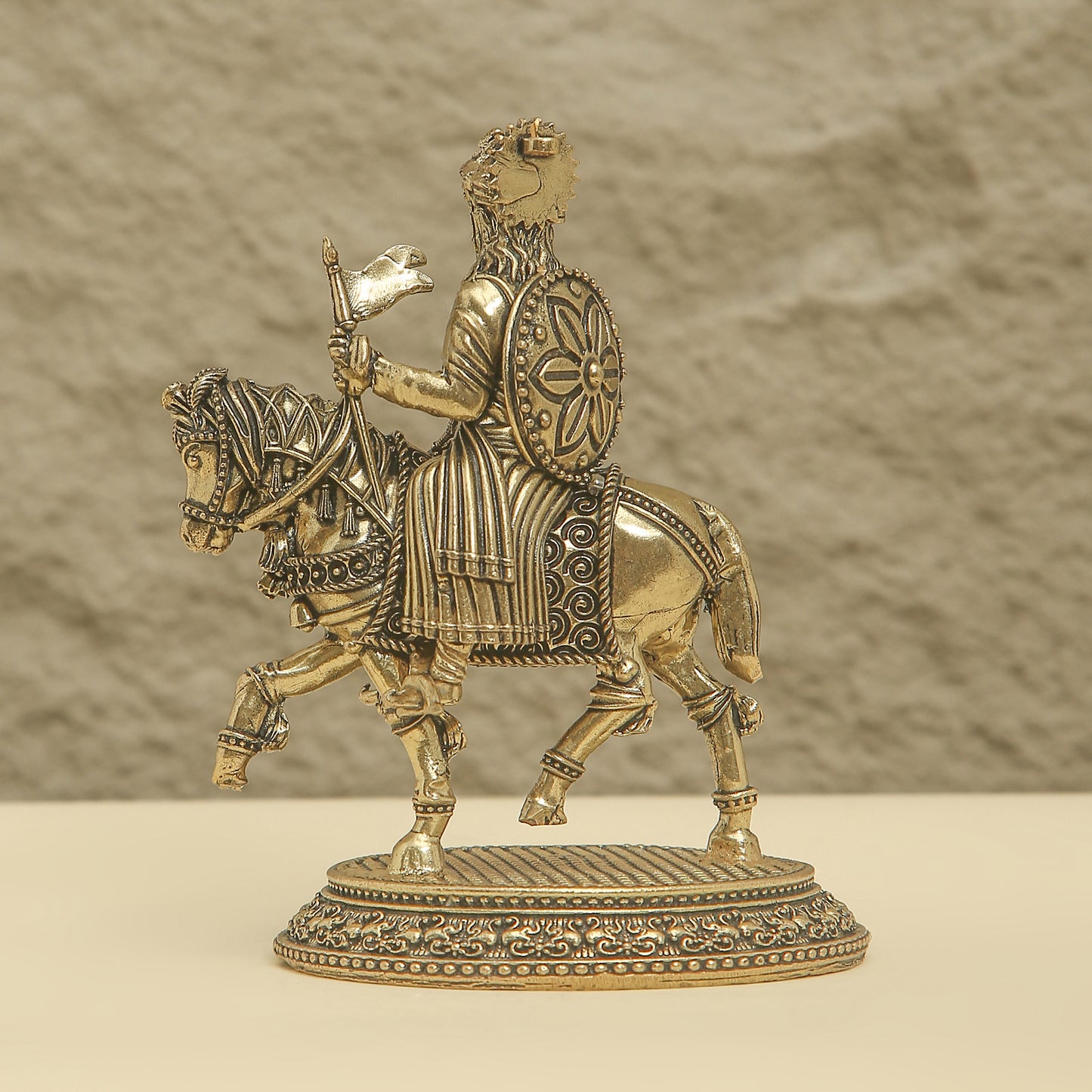 Bronze statue of a warrior on horseback with intricate details against a neutral background