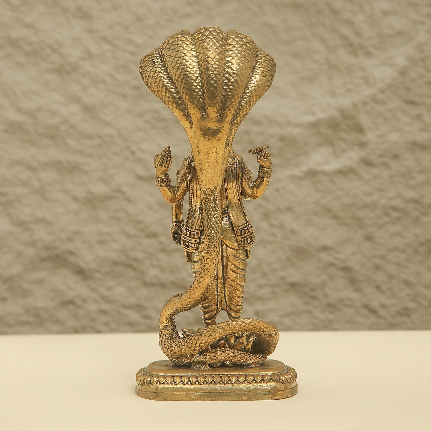 Bronze statue of a cobra with human figures on a textured background