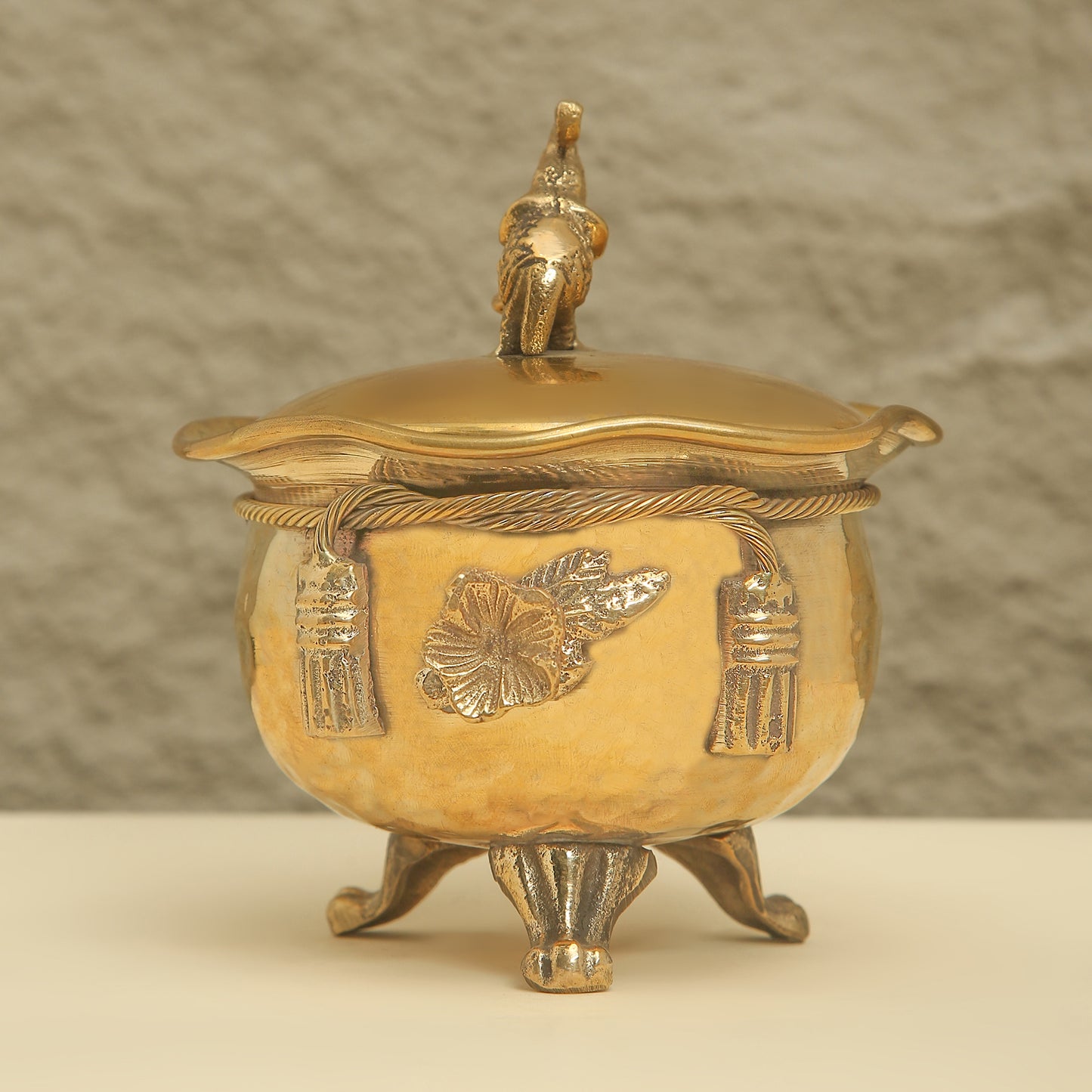 Gold decorative pot with lid on a beige background
