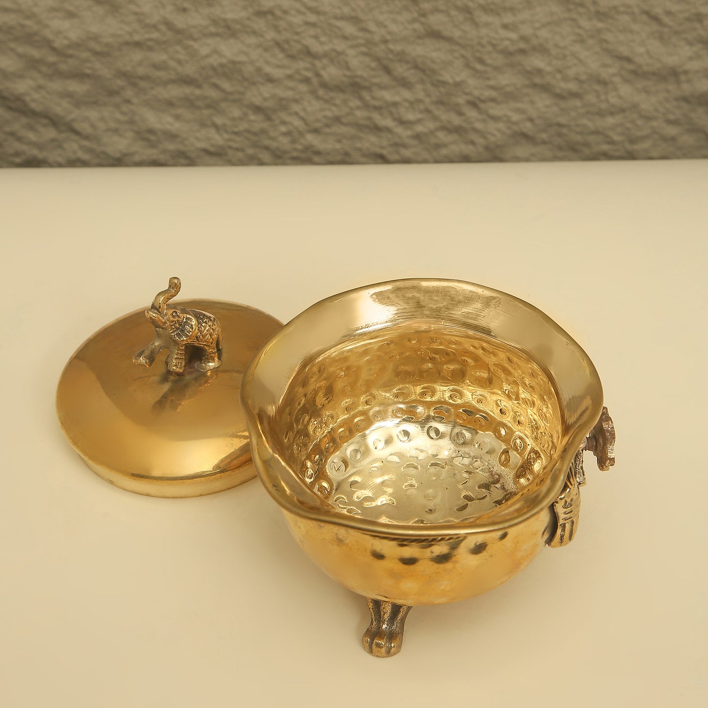 Gold decorative container with lid on a beige surface