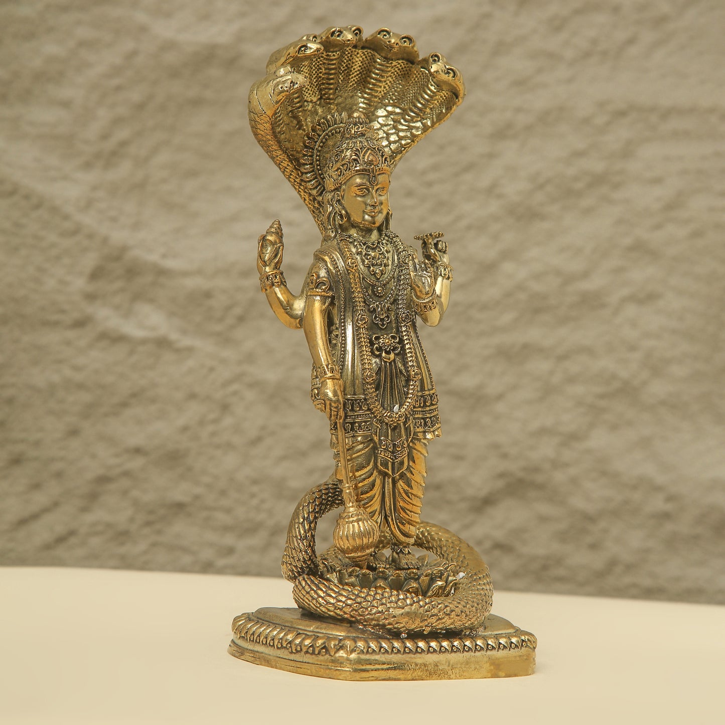 Gold-colored statue of a deity on a textured surface