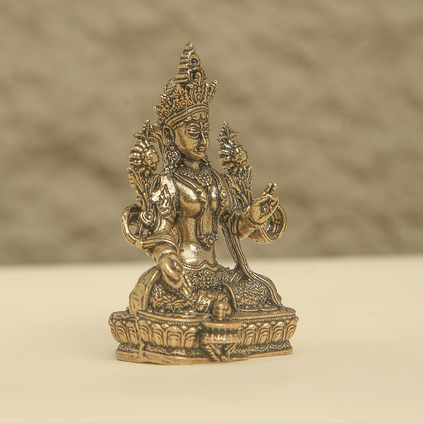 Bronze statue of a deity on a beige background