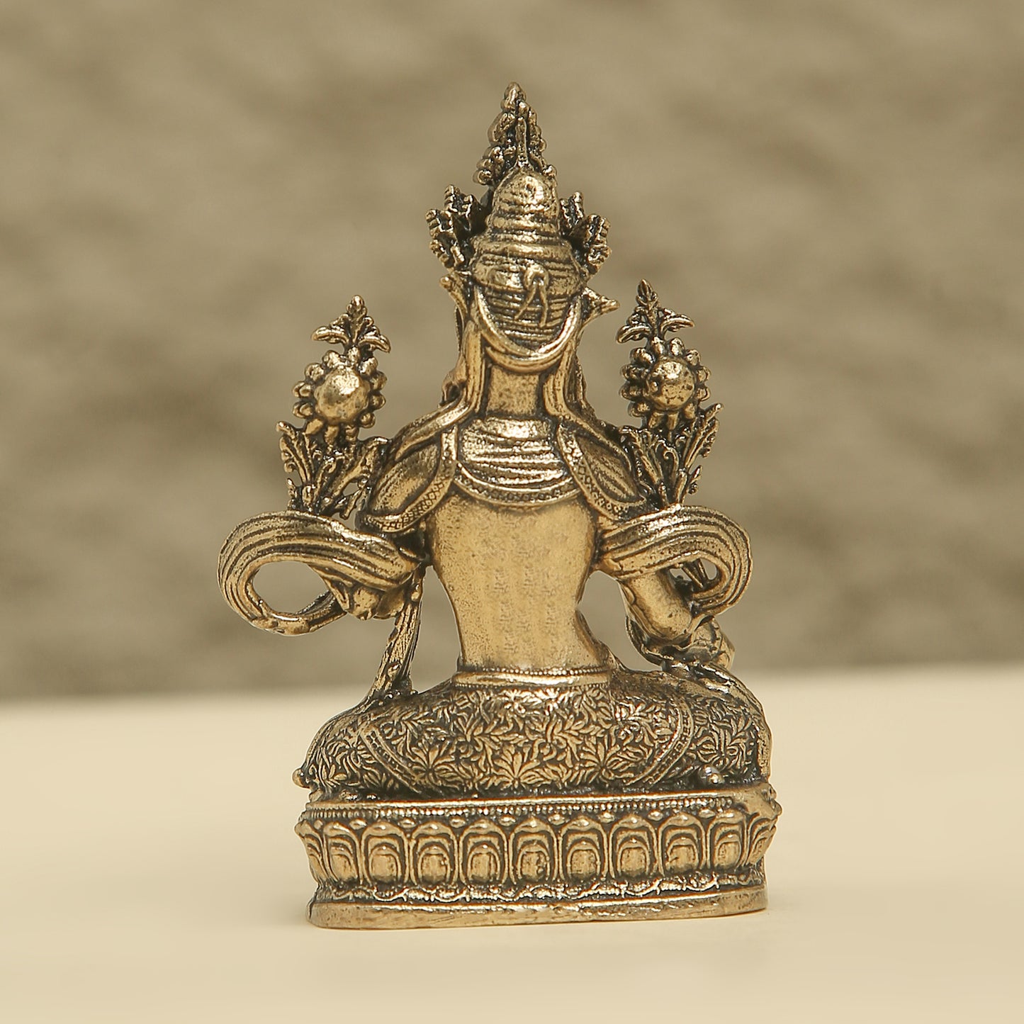 Bronze statue with intricate designs on a beige background