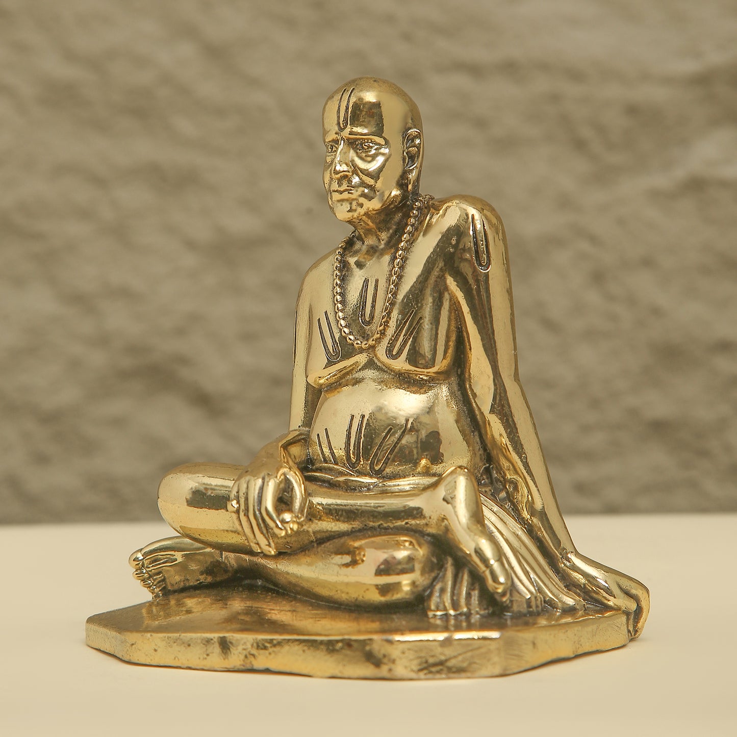 Gold statue of a seated figure on a beige background