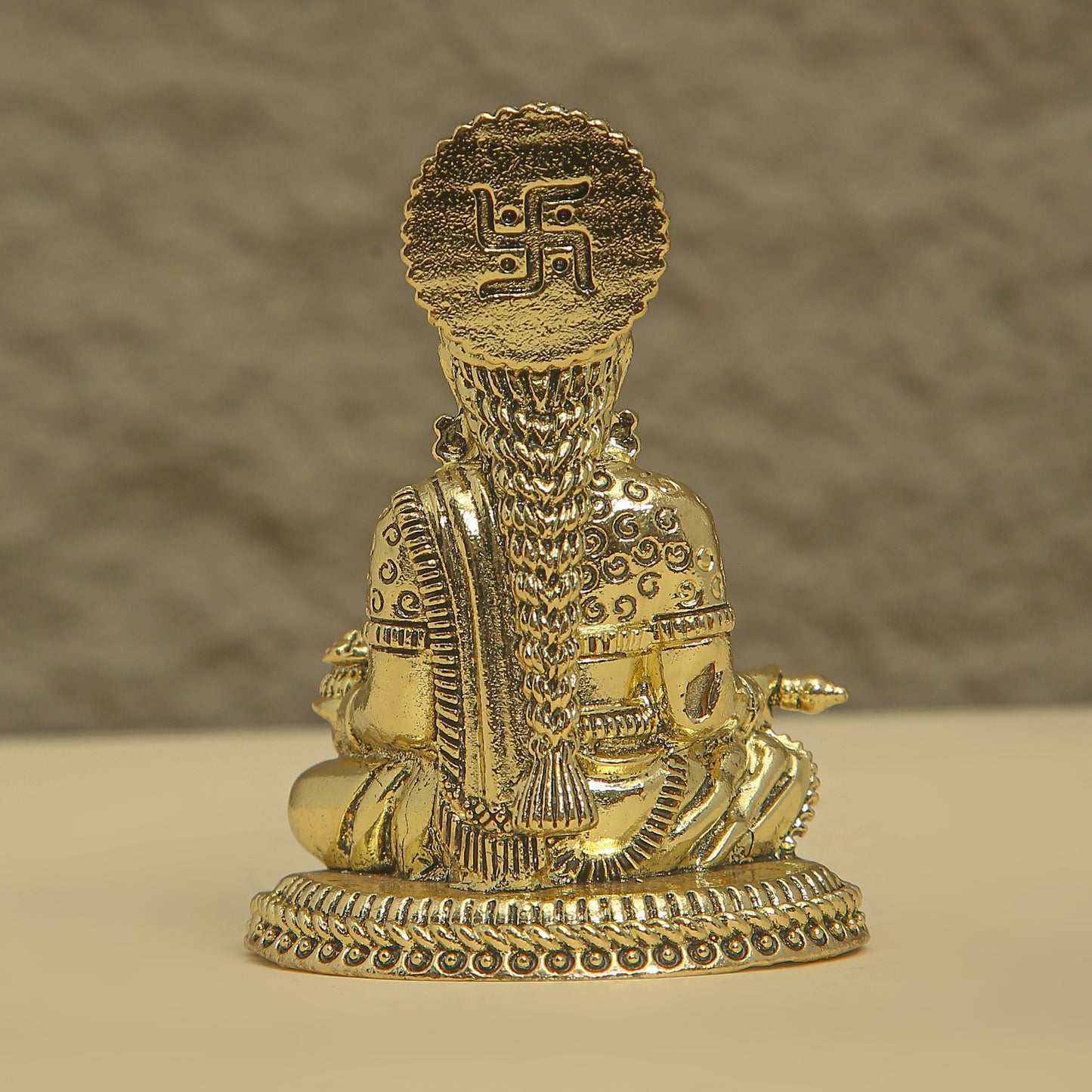 Gold-colored statue with a swastika symbol on a beige background