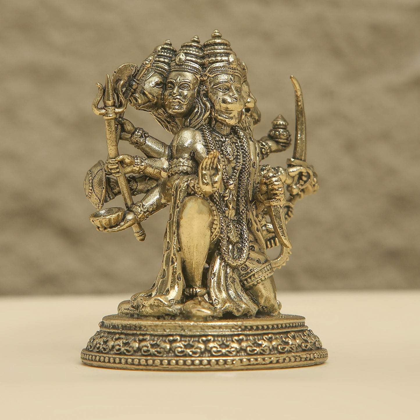 Bronze statue of a deity with multiple faces and weapons on a beige background