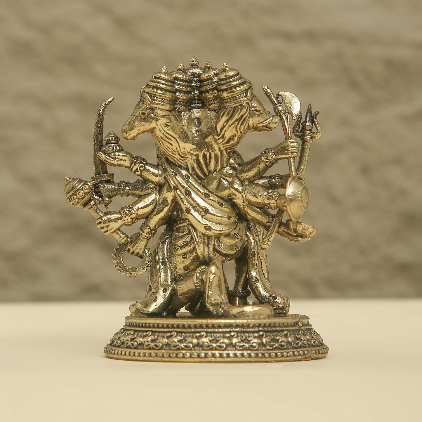 Brass statue of a multi-armed deity on a beige background