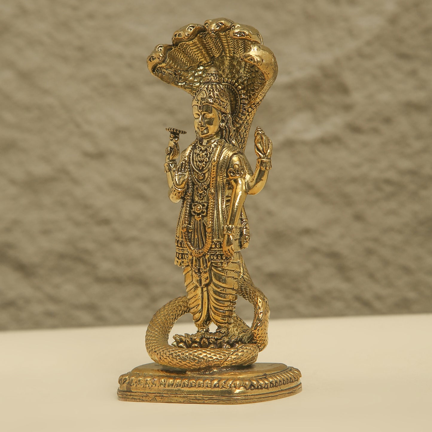 Gold-colored statue of a deity with intricate details on a textured background