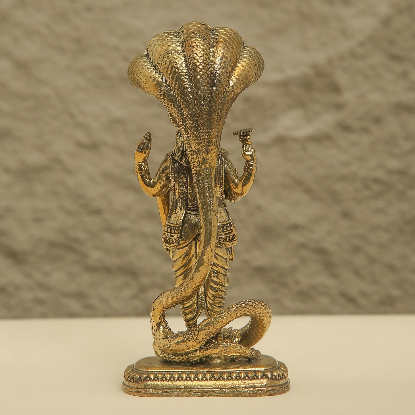 Bronze statue of a cobra with a person inside on a beige background