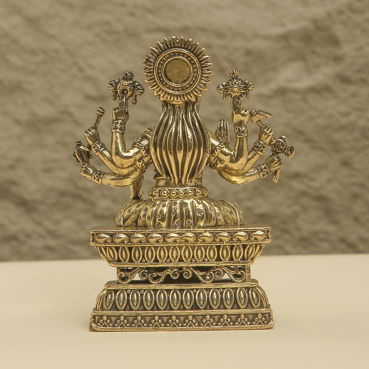 Decorative brass statue with intricate designs on a neutral background
