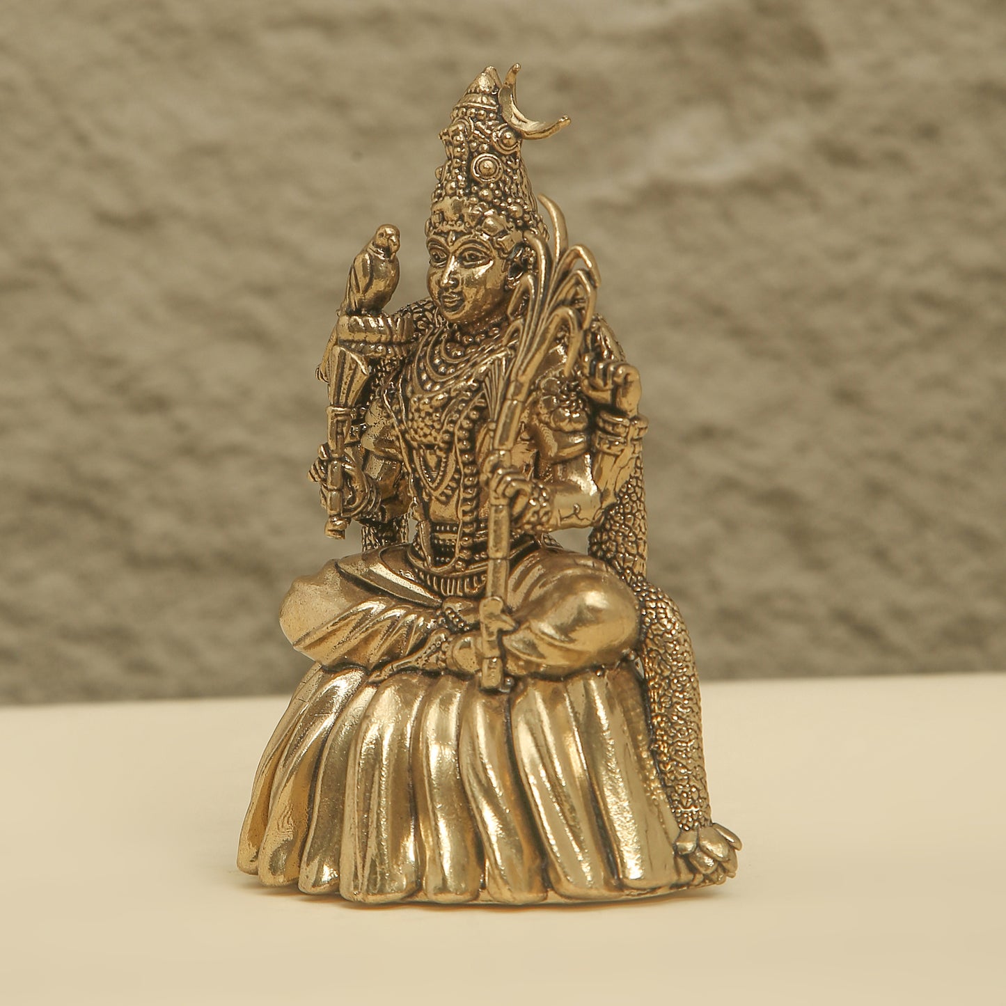 Gold-colored statue of a deity on a neutral background
