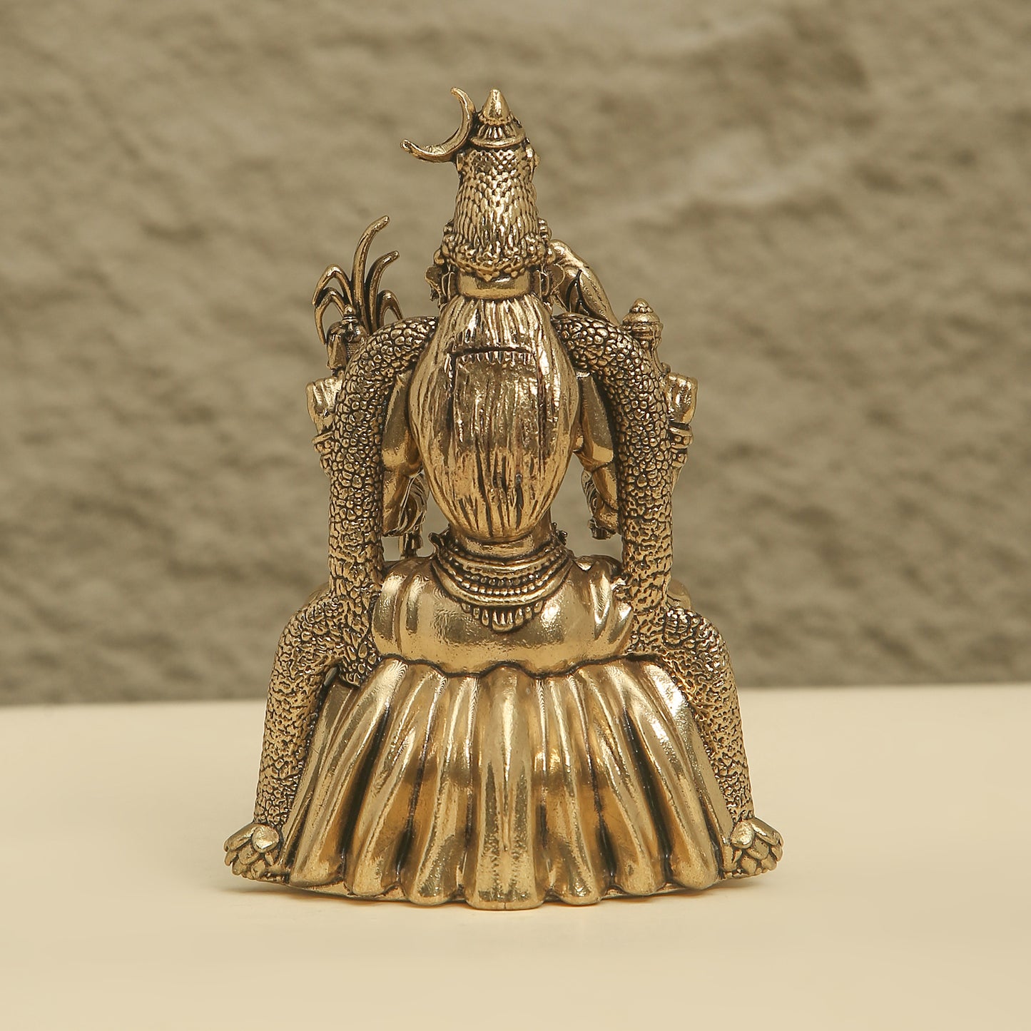 Gold-colored decorative object with intricate design on a neutral background