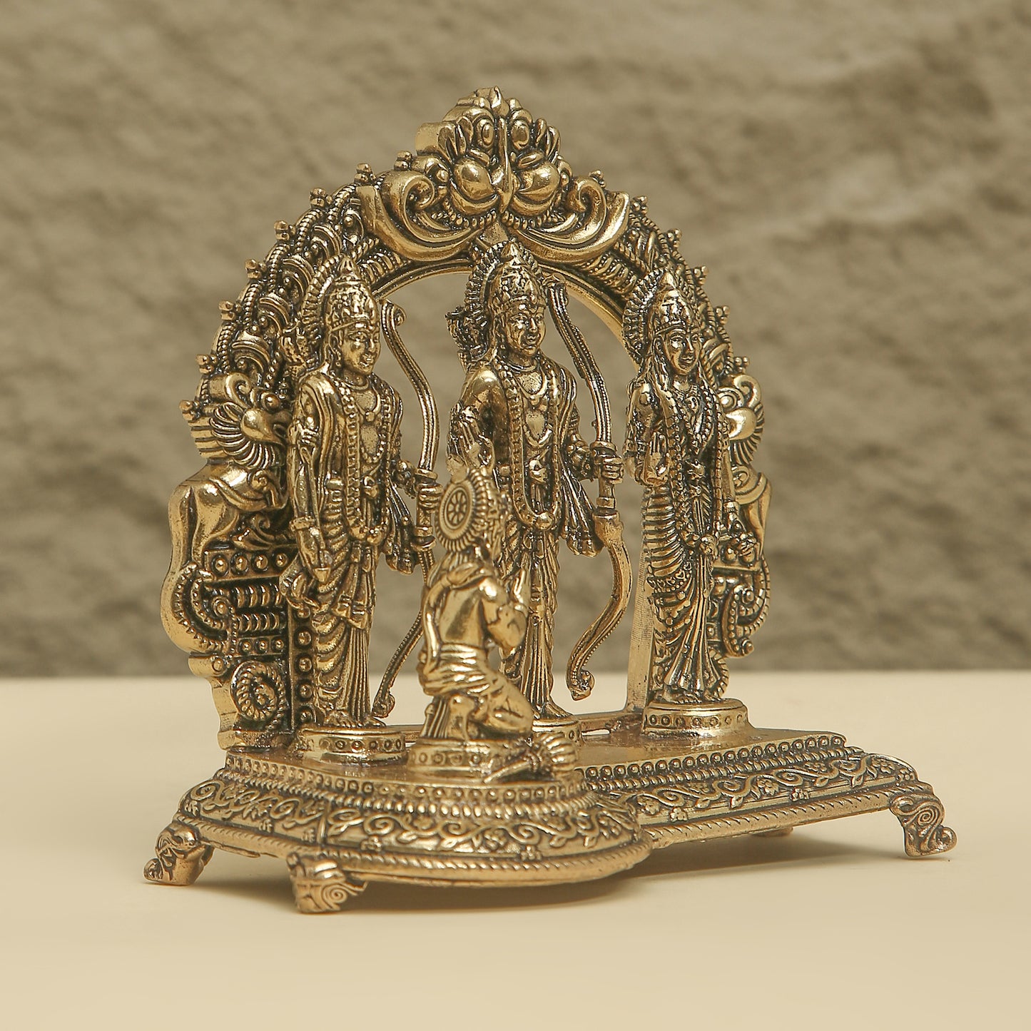 Decorative brass statue with intricate designs on a beige background